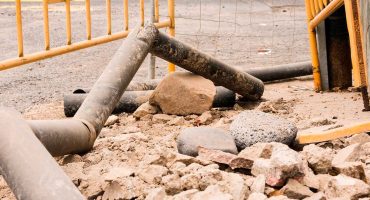 Ilustración de una excavadora trabajando en la instalación de tuberías subterráneas para redes de alcantarillado y agua potable.